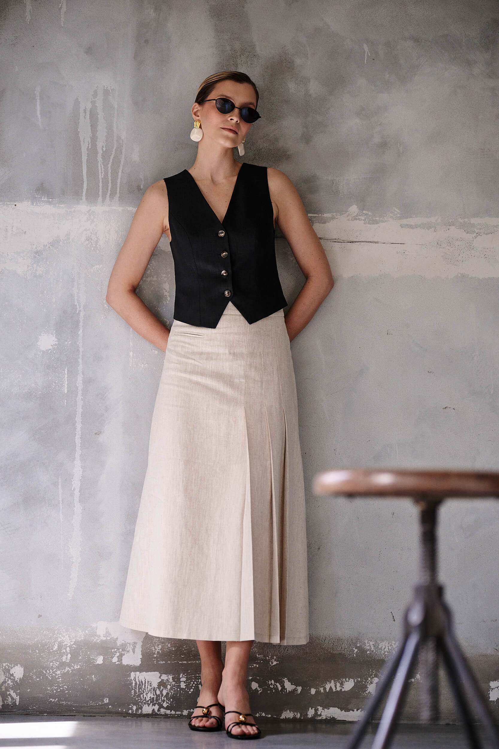 Minimalistyczna stylizacja od Aleksandry Markowskiej z czarną kamizelką i kremową spódnicą midi w stylu smart casual, idealna na lato.