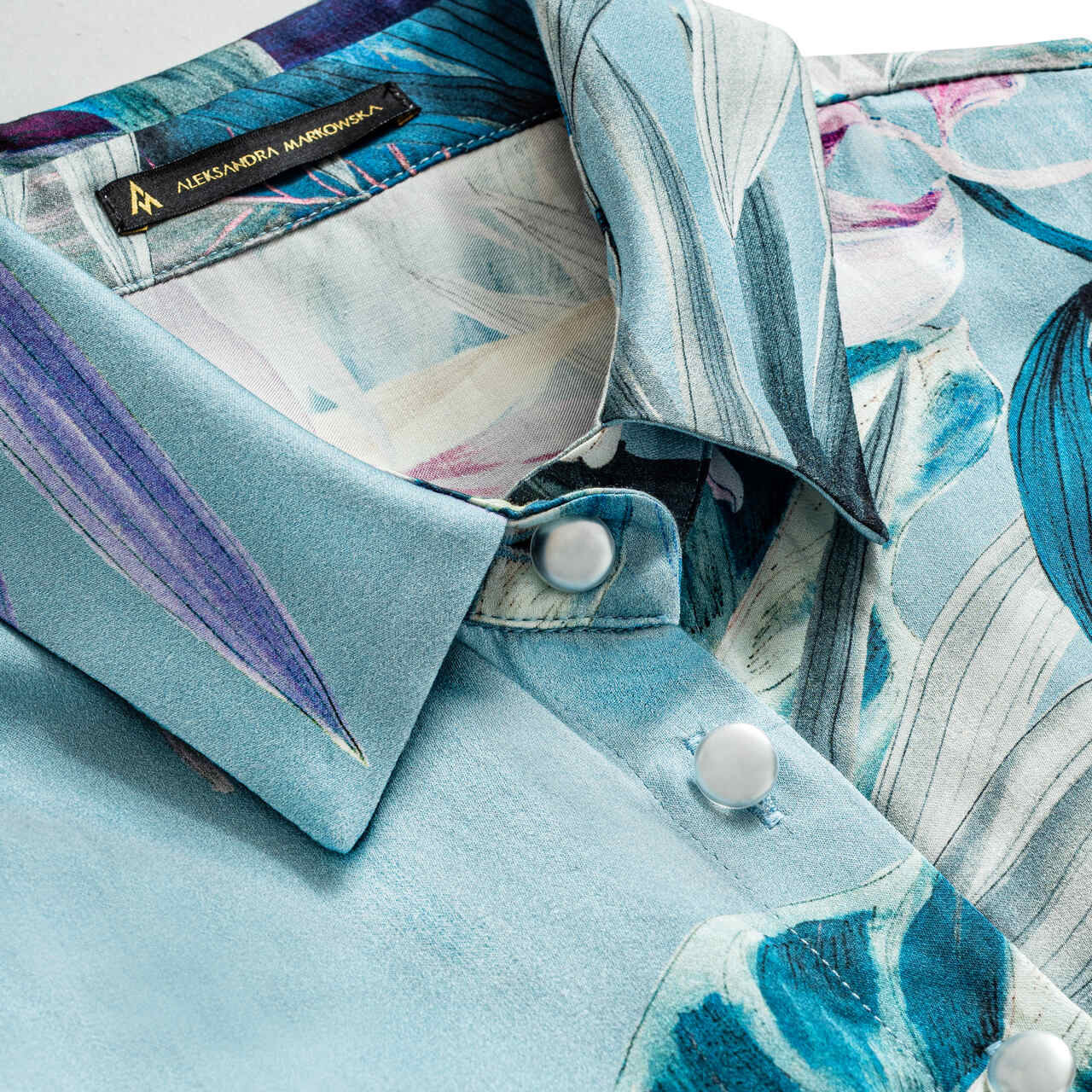 Zbliżenie na kwiatowy wzór i eleganckie wykończenie sukienki premium Aleksandry Markowskiej.