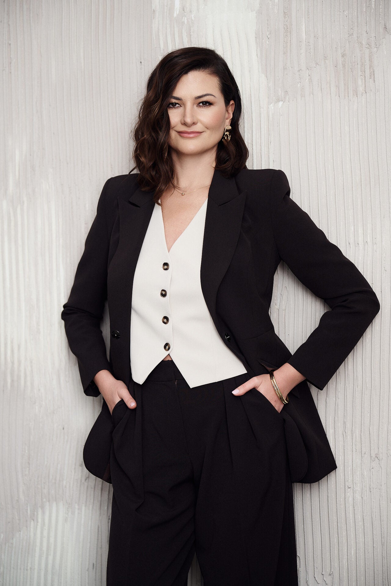 Biała kamizelka z ozdobnymi guzikami noszona na gołe ciało – nowoczesna stylizacja z szerokimi spodniami palazzo Asti