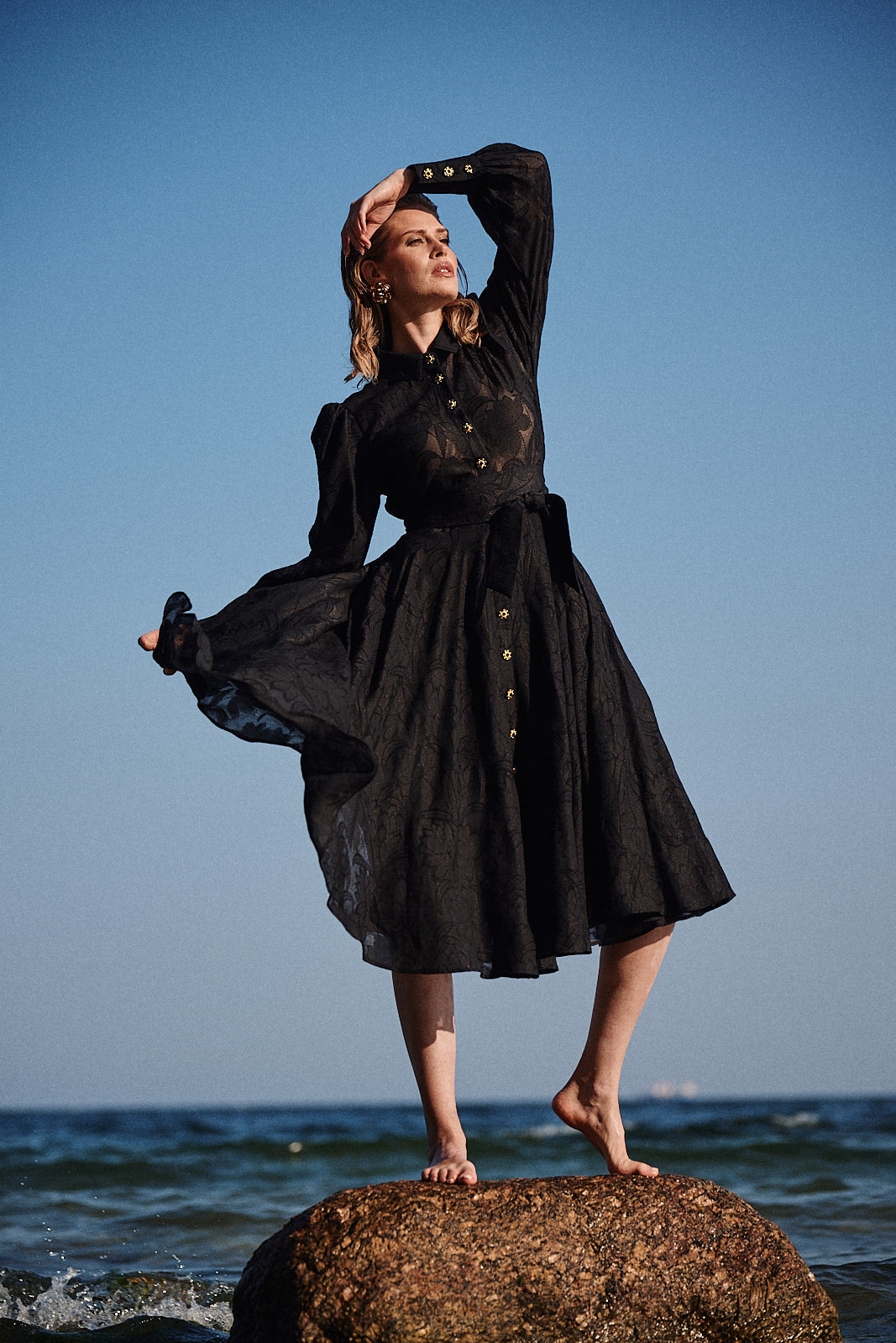 Aleksandra Markowska i wieczorowa elegancja – modelka w czarnej sukni z transparentnym wykończeniem, bufiastym, długim rękawem.