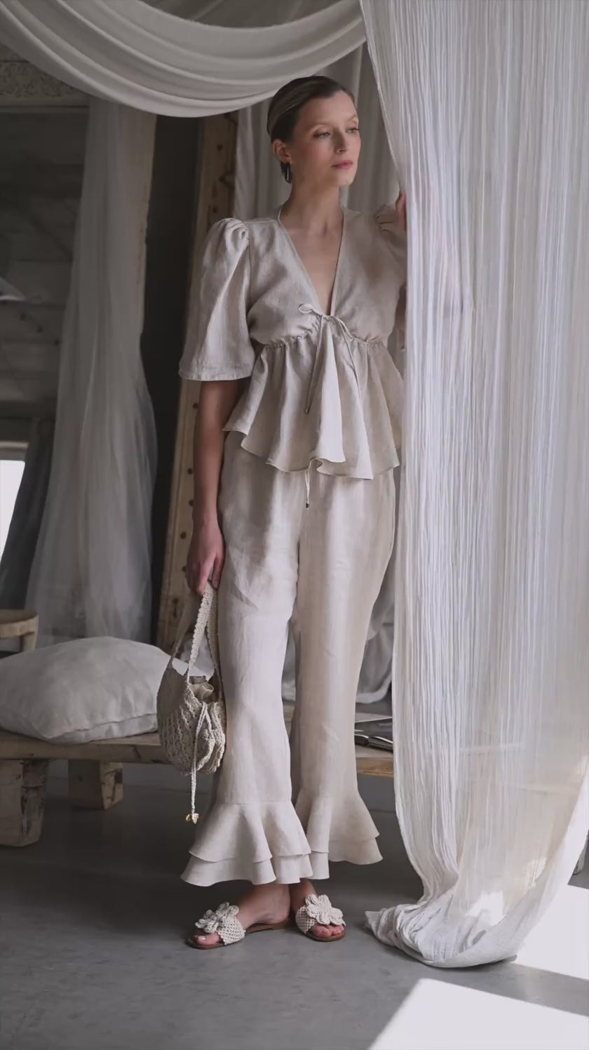 Letni komplet lniany Silvana Avorio – bluzka i spodnie z falbaną projektu Anny Markowskiej. Stylowy, kobiecy look w naturalnym odcieniu avorio, wykonany w 100% z certyfikowanego hiszpańskiego lnu – idealny na lato.